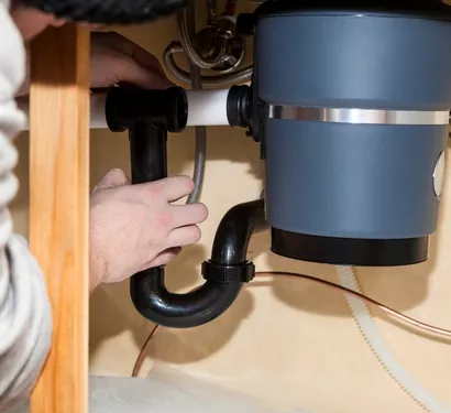 Technician installing a garbage disposal in a Tempe kitchen