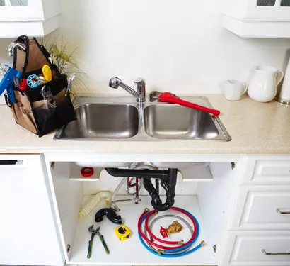Plumber repairing kitchen plumbing in a Tempe home